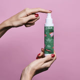 Des mains de femme tiennent devant un fond rose un flacon de gel lubrifiant intime de la marque Goliate