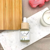 Un sérum anti-imperfections Cosmoz posé sur une planche en marbre, sur une nappe beige