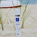 Un flacon de crème hydratante de la marque Passion Marine posé dans le sable sur une plage bretonne