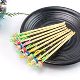 Neuf cure-oreille en bois posés dans une coupelle noire en céramique