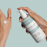 Sur fond bleu-vert, des mains de femme tiennent un flacon de gel-crème nettoyant rééquilibrant de la marque Réjence