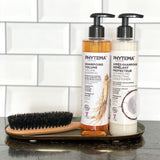 Dans une salle de bain posé sur un plateau métallique à droite d'une brosse à cheveux en poils de sanglier, le shampoing volume et l'après-shampoing démêlant protecteur de la marque Phytema