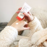 Une femme habillée d'un pull fourré applique de la crème pour les mains Lady Green