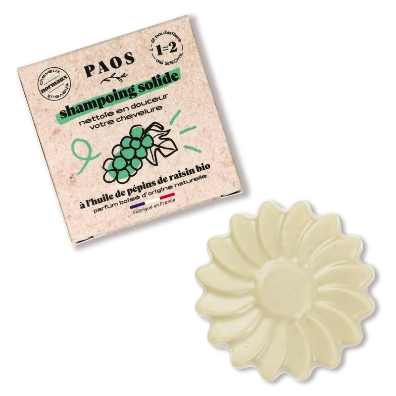Sur fond blanc, un shampoing solide PAOS en forme de marguerite et son étui en carton