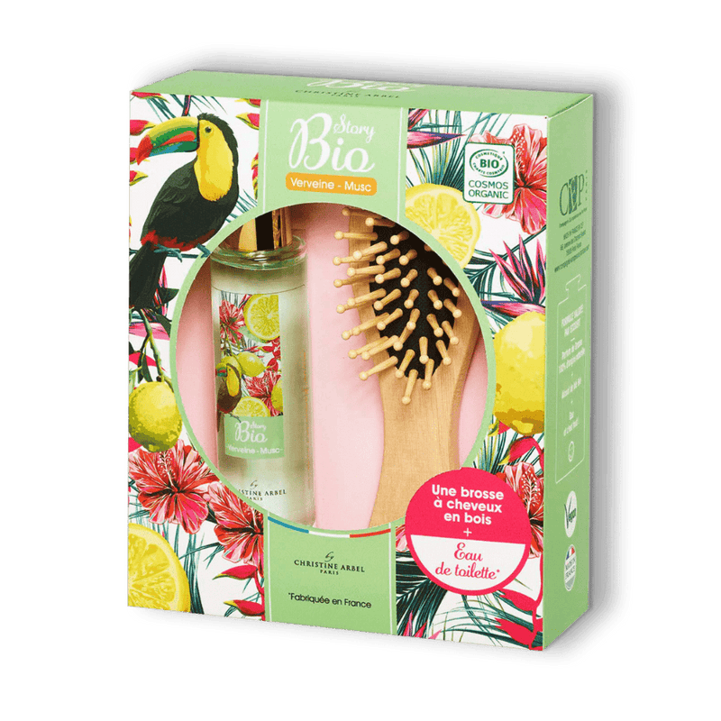 Sur fond transparent un coffret-cadeau avec une eau de toilette Story Bio Verveine Musc pour femme et une brosse à cheveux en bois