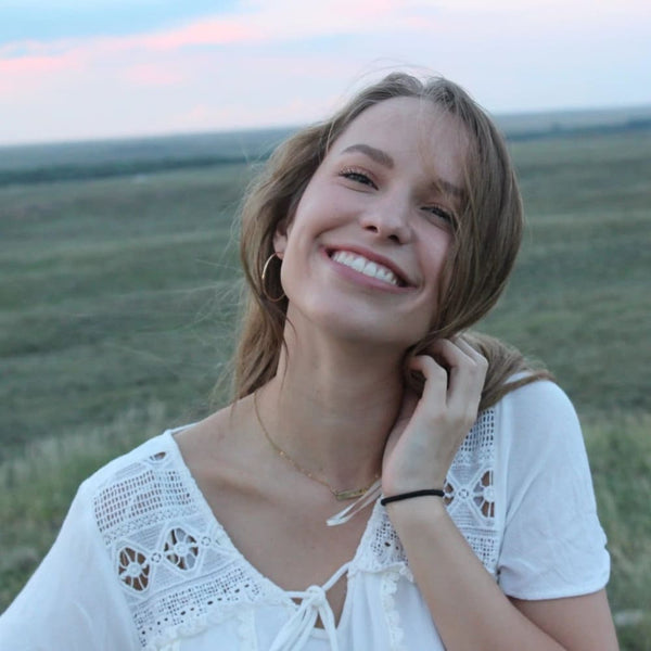 Une femme blanche en pleine nature dans un champ sourit