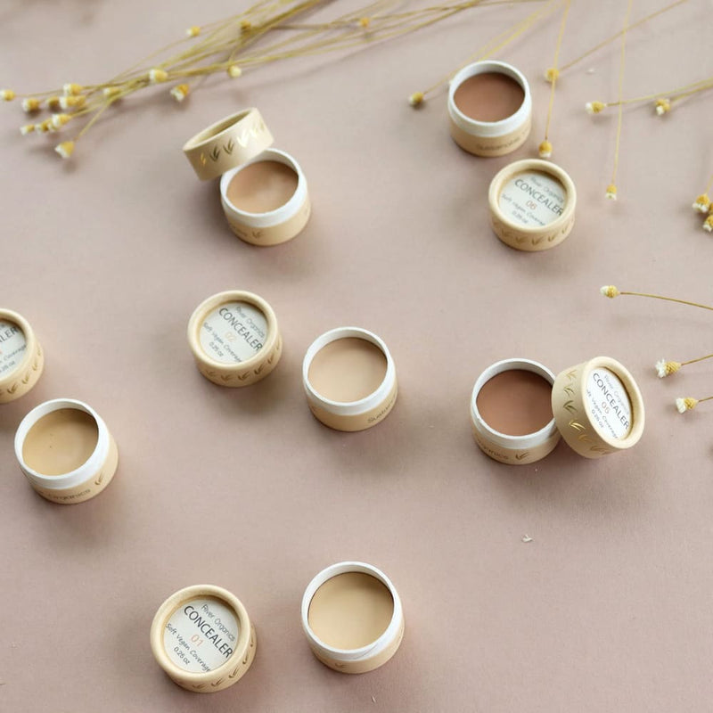 Sur un fond beige, des pots d'anti-cernes de la marque River Organics