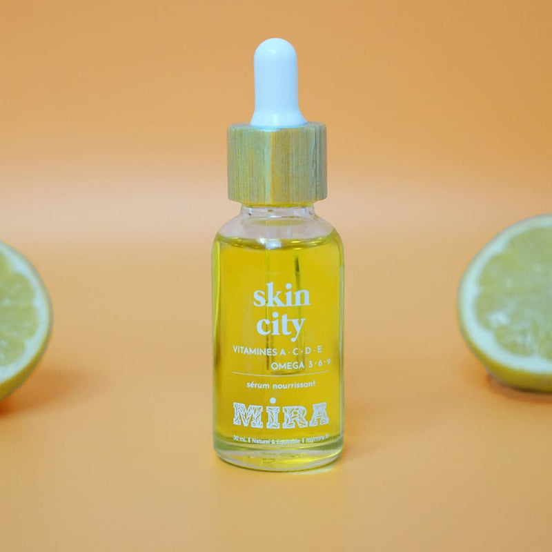 Sur un fond jaune orangé avec deux citrons coupés en deux, au milieu est posé un sérum visage Skin City de la marque My Mira