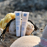 Sur une plage, posé à côté d'un chapeau de paille un contour des yeux et un soin lèvres de la marque Passion Marine